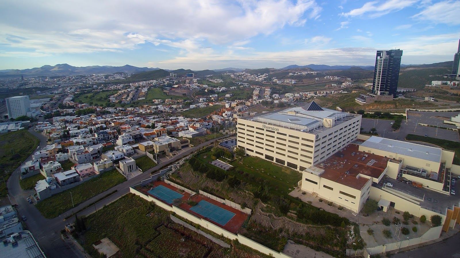 Aerial view of a city with a hotel and pool in the foreground
